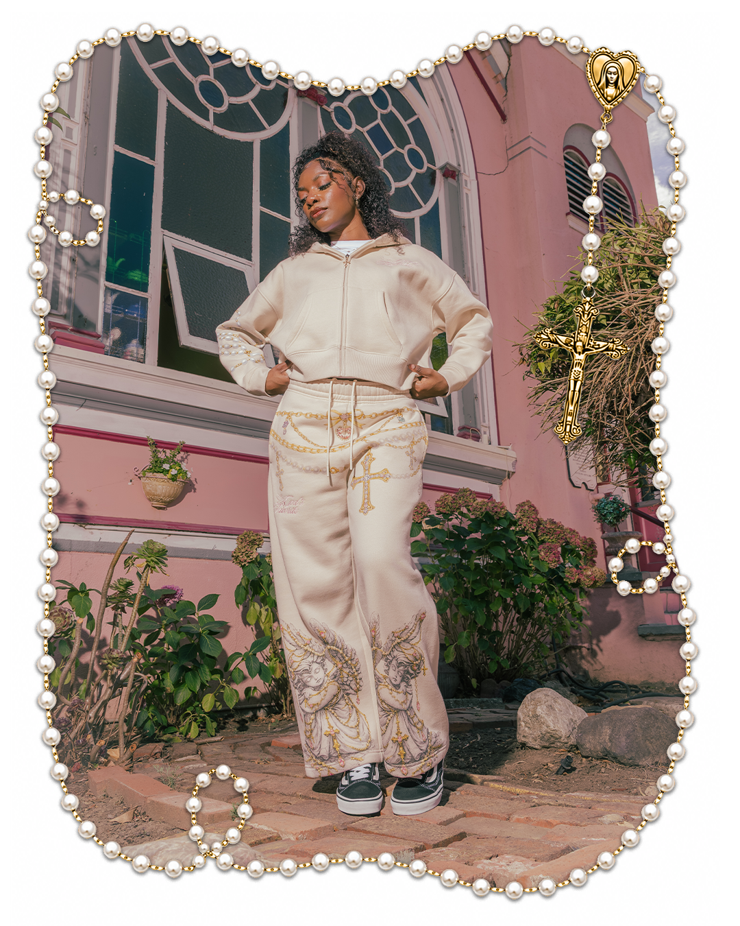 Person in stylish beige outfit posing by a pink building with plants.