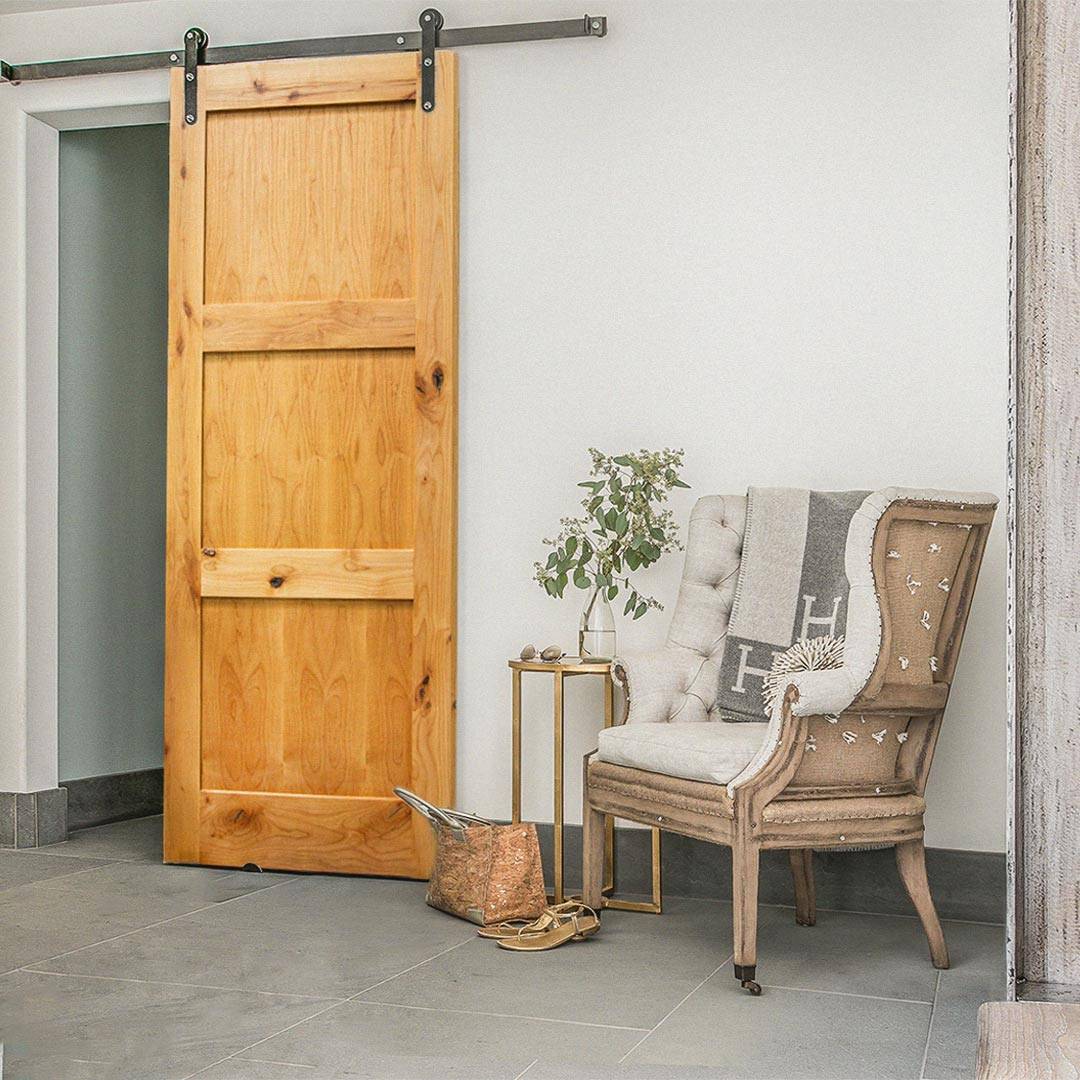Scene with a chair and the shaker three panel sliding barn door design by RealCraft