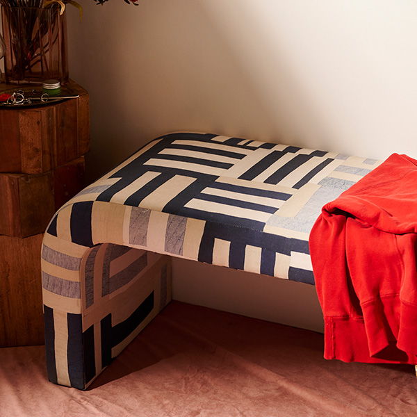 A patterned bench with a red throw draped over it.