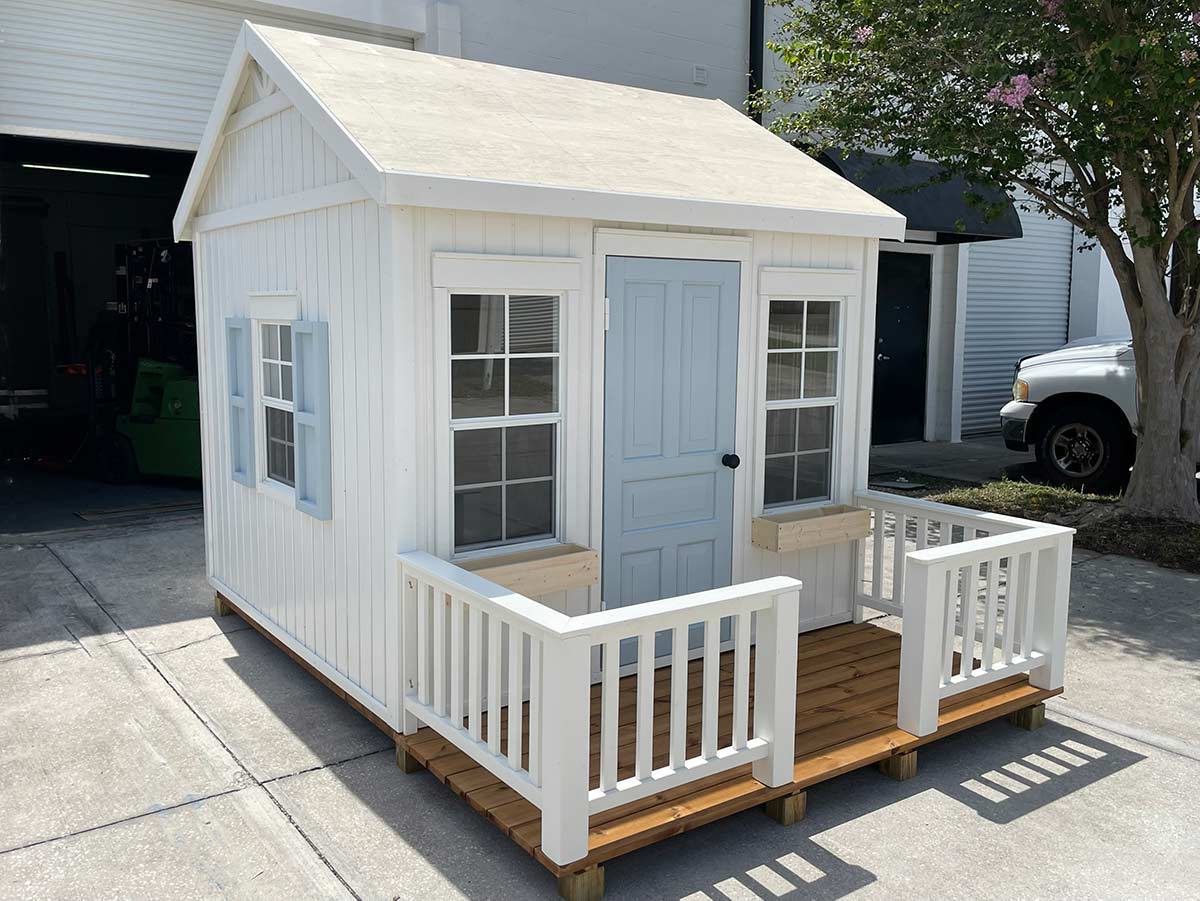 Custom Playhouse with  light gray window shutters and door, wooden terrace with white wooden railings by WholeWoodPlayhouses