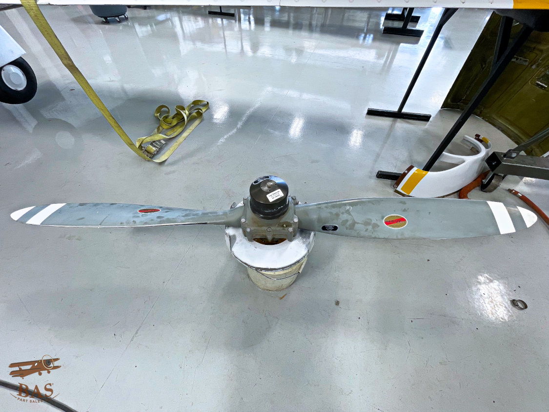 Propeller on a workbench, with a white floor and tools in background.