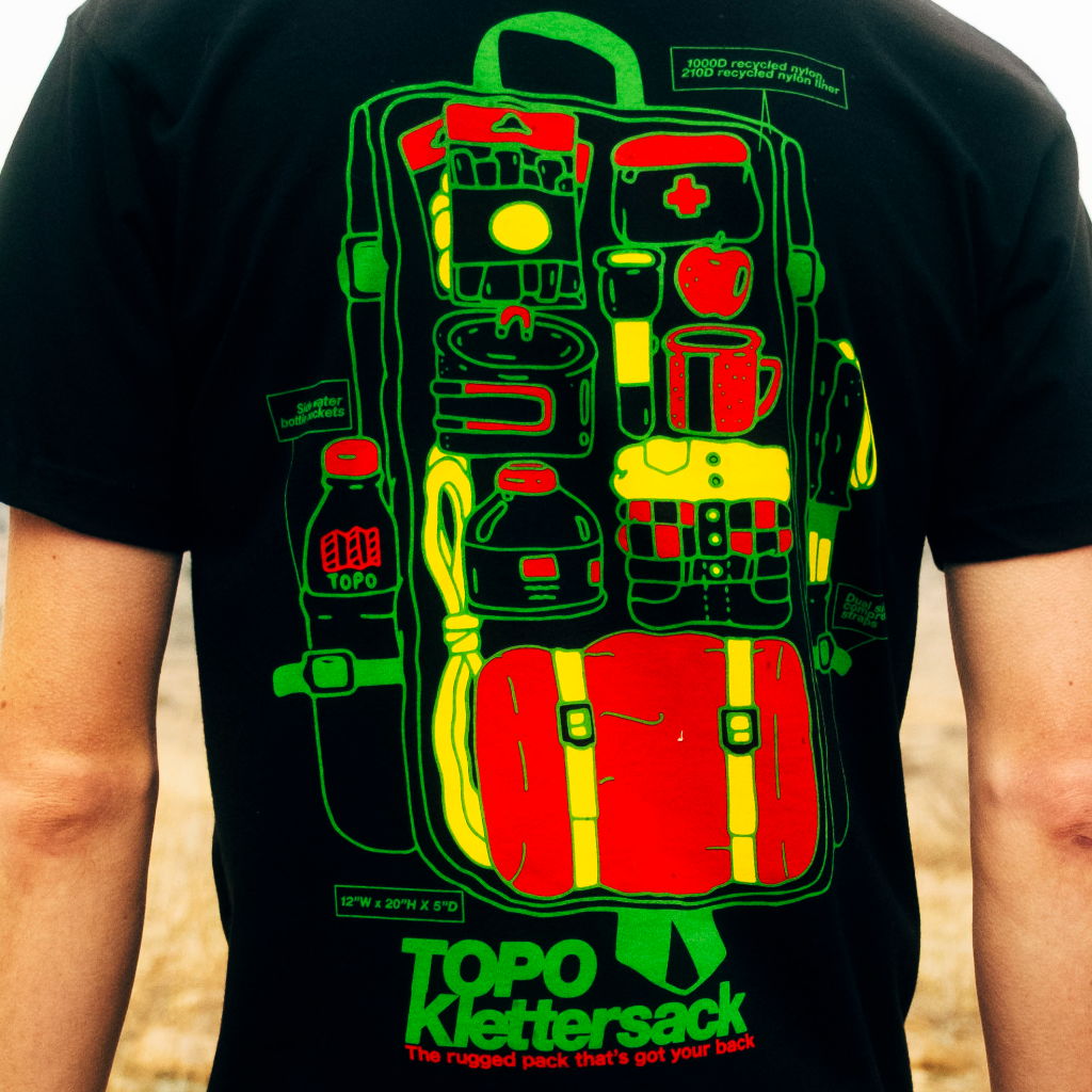 Person wearing a black t-shirt with colorful backpack graphic design.