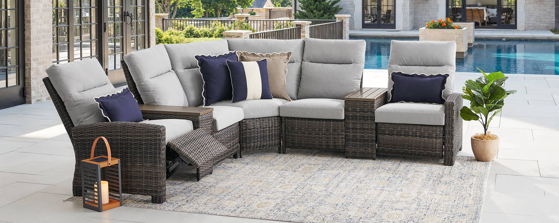 Outdoor sectional sofa with cushions, plants, and pool in the background.