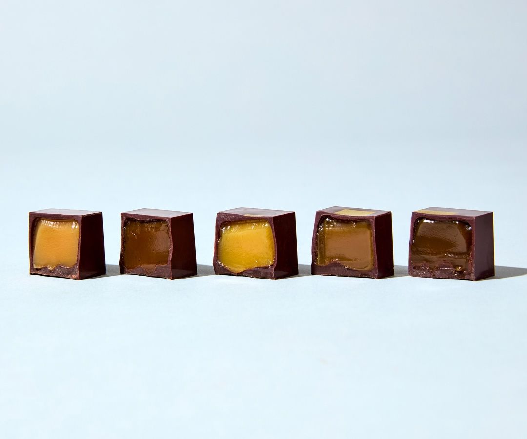 Five chocolate squares with different colored fillings on a light background.
