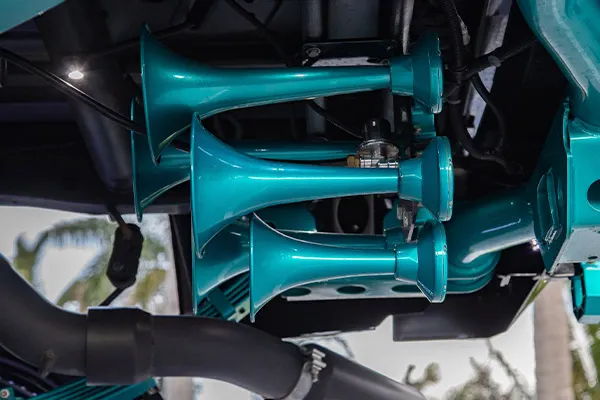 Close-up underside view of teal Katrina 544K train horn bells mounted under Brandon's 2018 Silverado 2500, install photo 3
