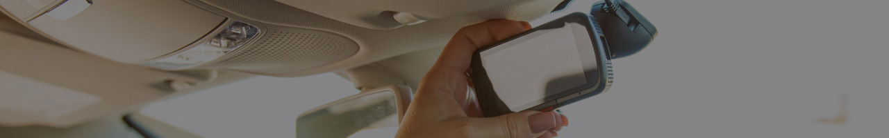 A close-up of a hand holding rear view mirror against a blurred background.