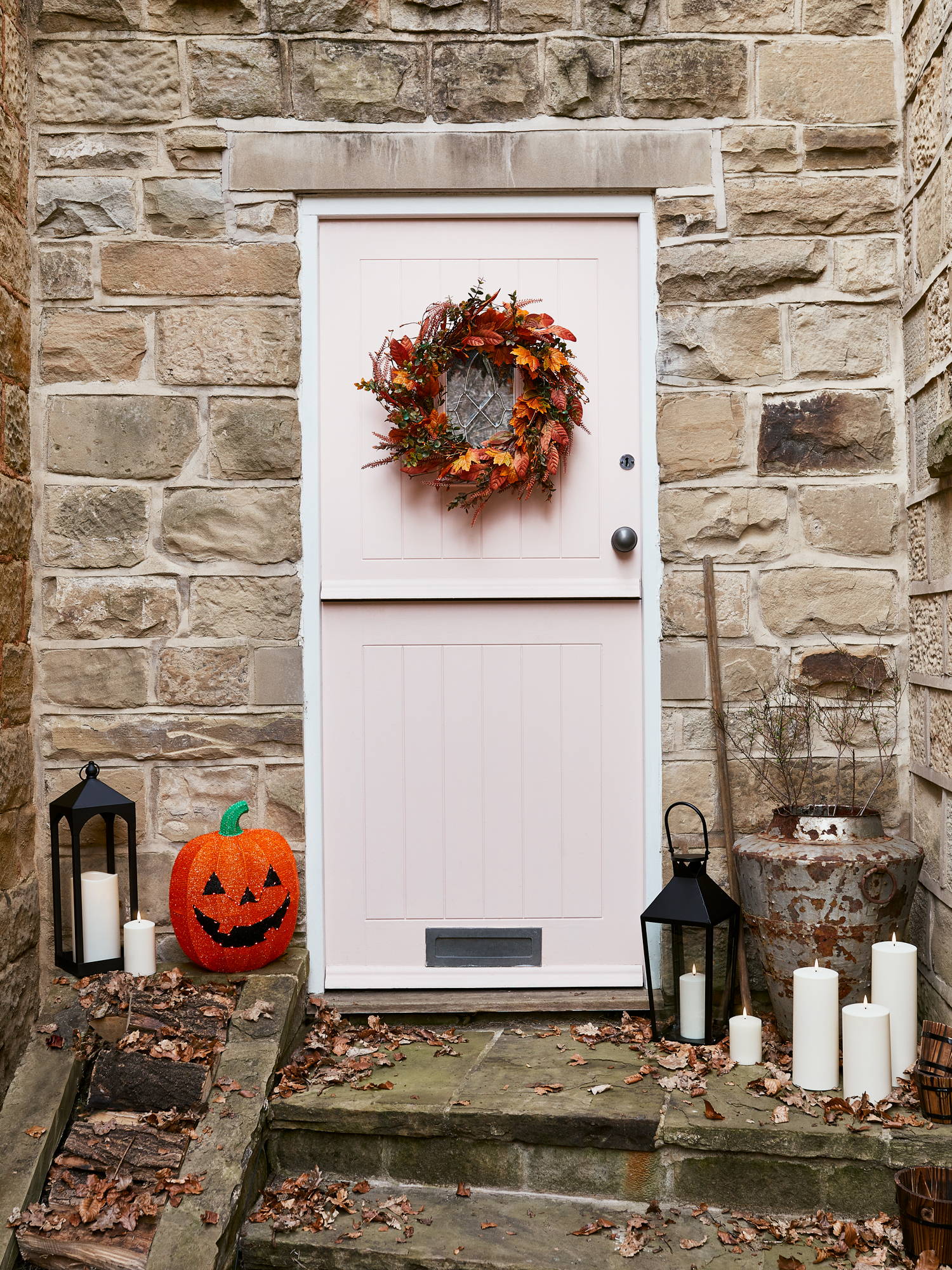 Outside porch decorated with an Autumn wreath, lanterns, candles and a pumpkin.