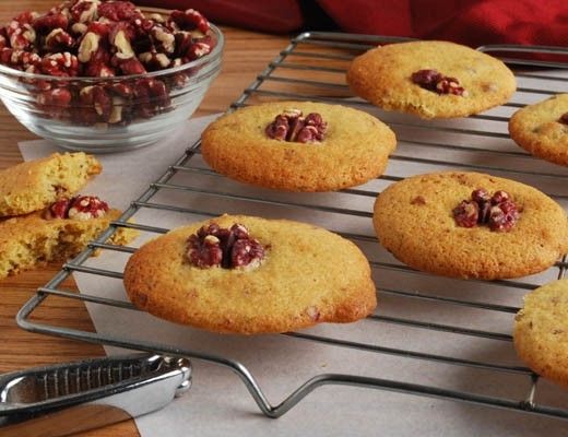 Cookies on a cooling rack with nuts in a bowl.