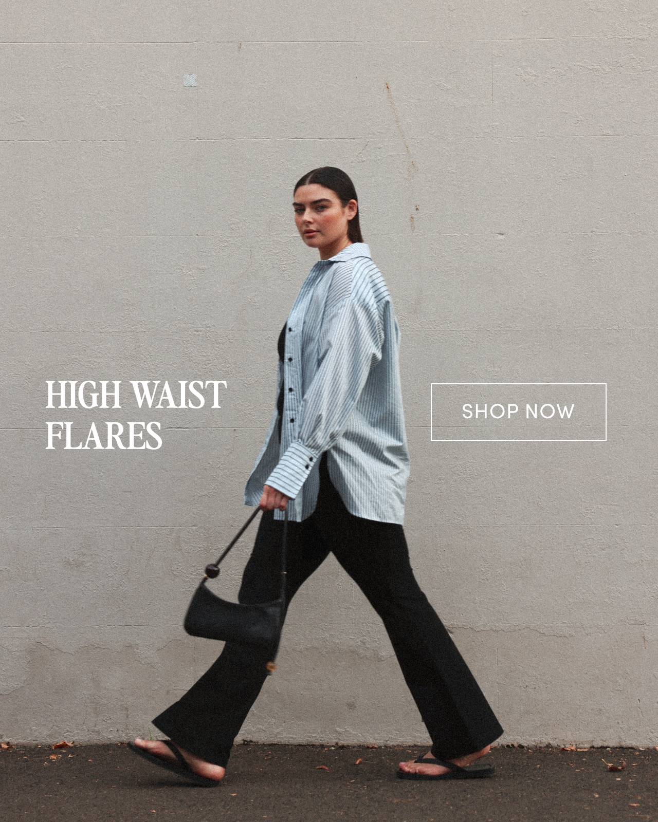 Model wearing high waist flares, walking against a plain wall backdrop.