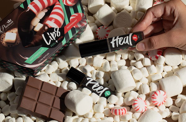 Lip products and chocolate on a bed of marshmallows and peppermint candies.