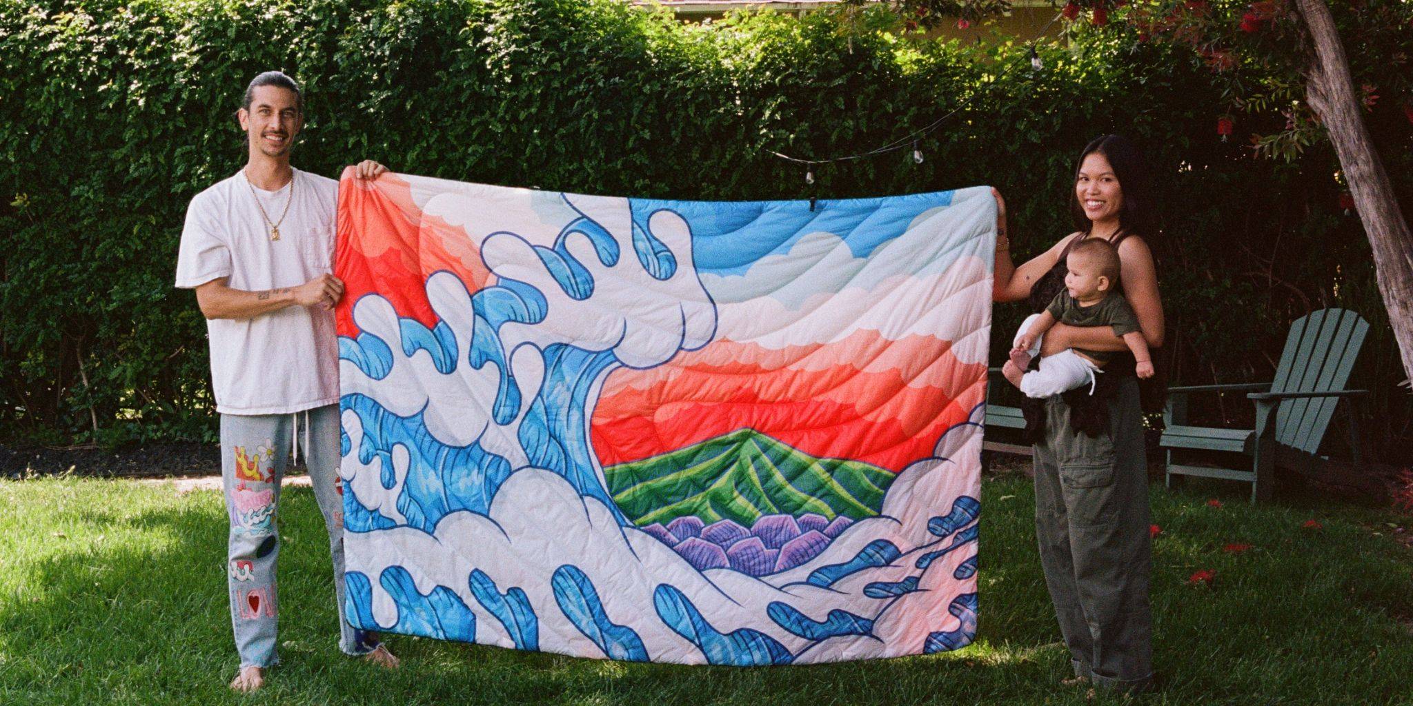 Aaron Kai, his wife, and second child hold up the Rumpl Original Puffy Blanket - Hokusai Great Wave