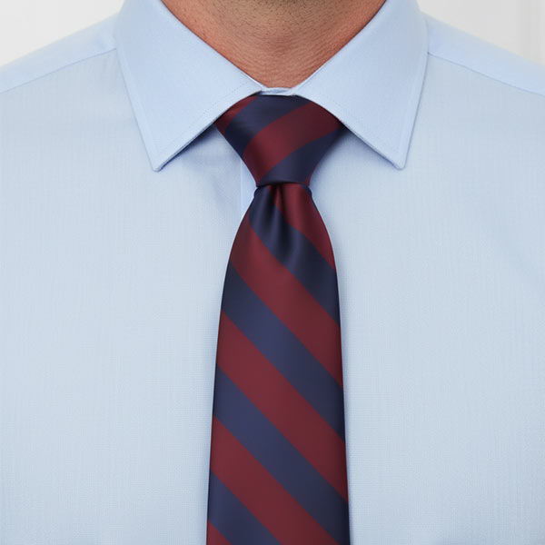 Closeup of a man wearing a navy and maroon striped tie with a blue dress shirt