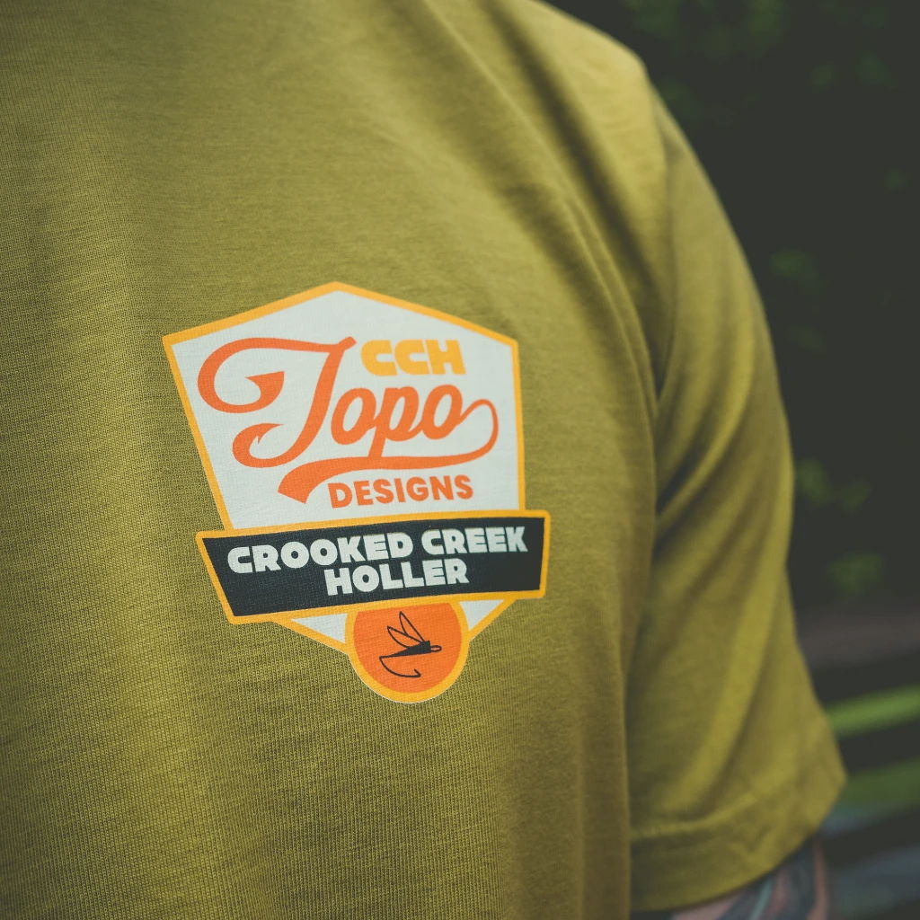 Person wearing an olive green shirt with a logo that reads 