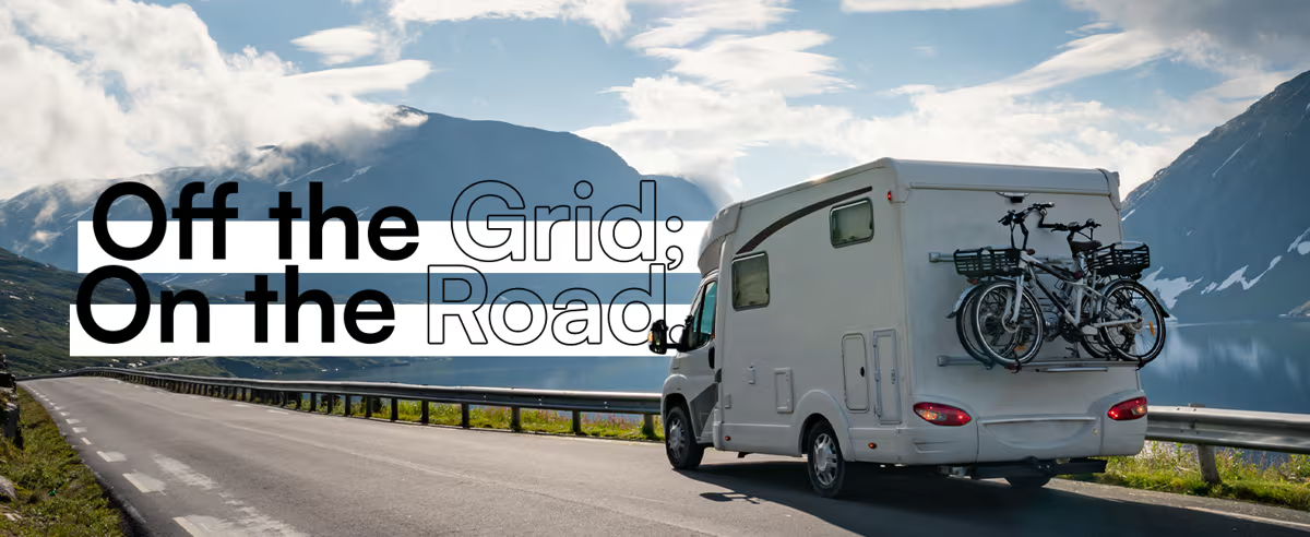 A camper van on a scenic road with mountains in the background.