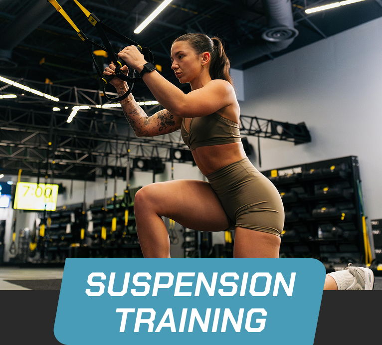 Woman performing suspension training exercise in a gym setting.