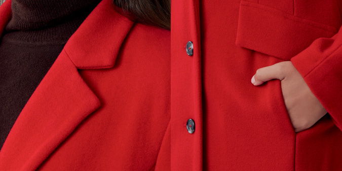 Close-up of a red coat with a hand in the pocket.