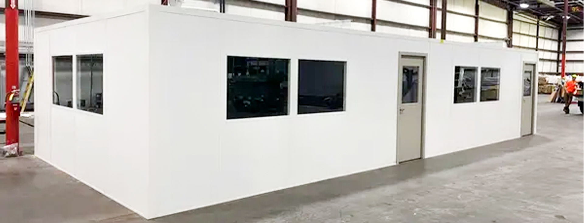 White modular building with windows in an industrial setting.