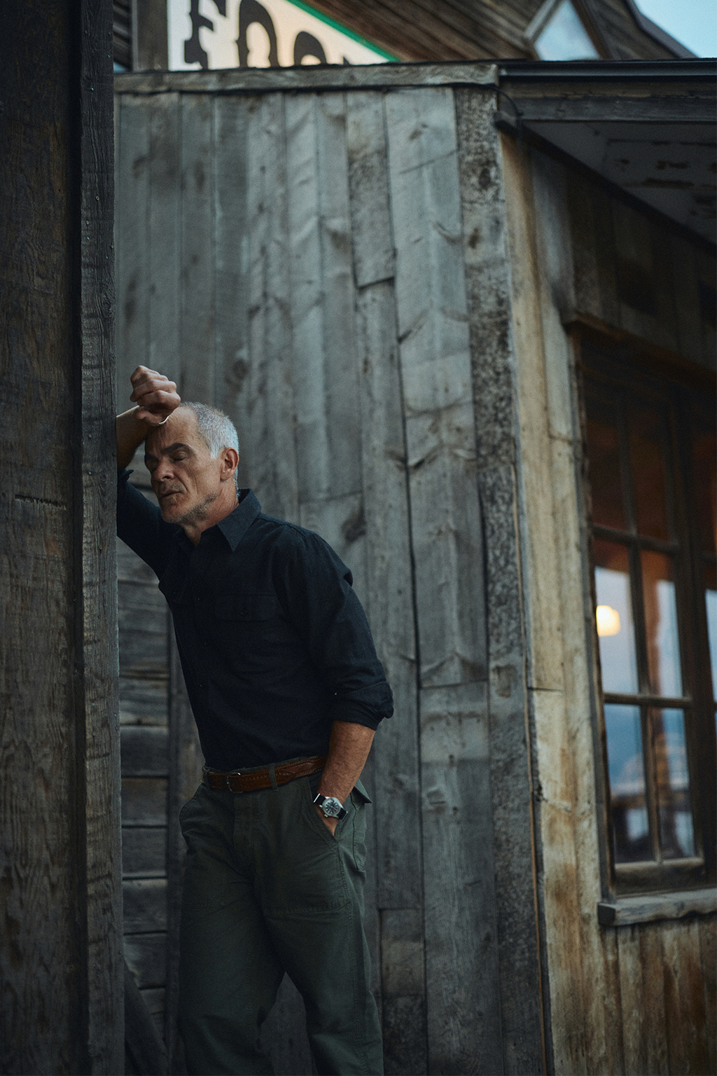 Michael Kelly outside the Old Saloon at dusk wearing the Rivay Miles Brushed Flannel Shirt and Series II Garment Dyed Utility Pant in Vintage Olive