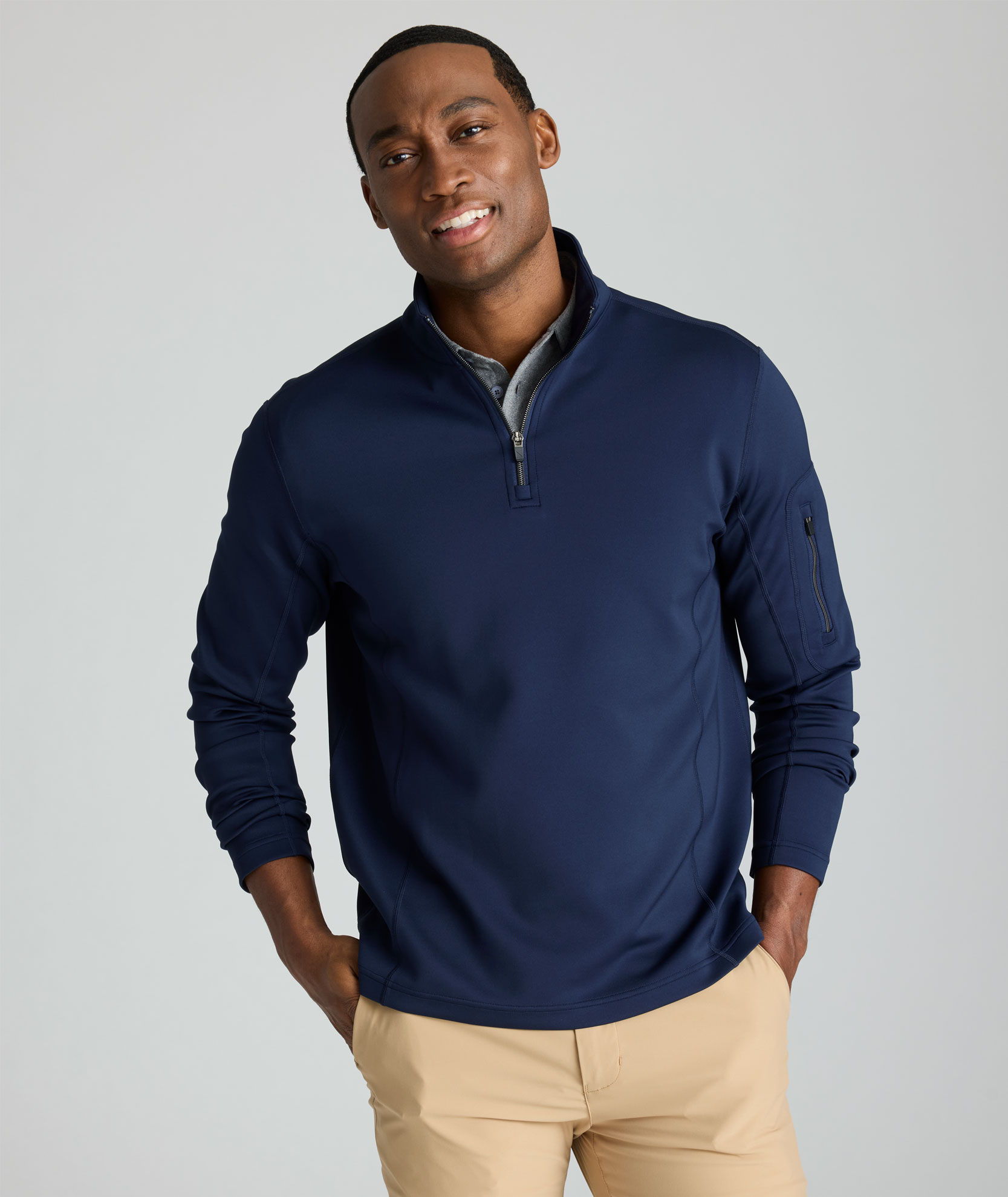 Man smiling in a navy quarter-zip sweater and beige pants.