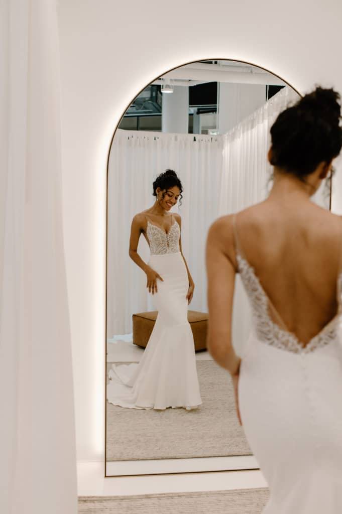 Bride looking in an arch mirror wearing the Grace Loves Lace Lena gown