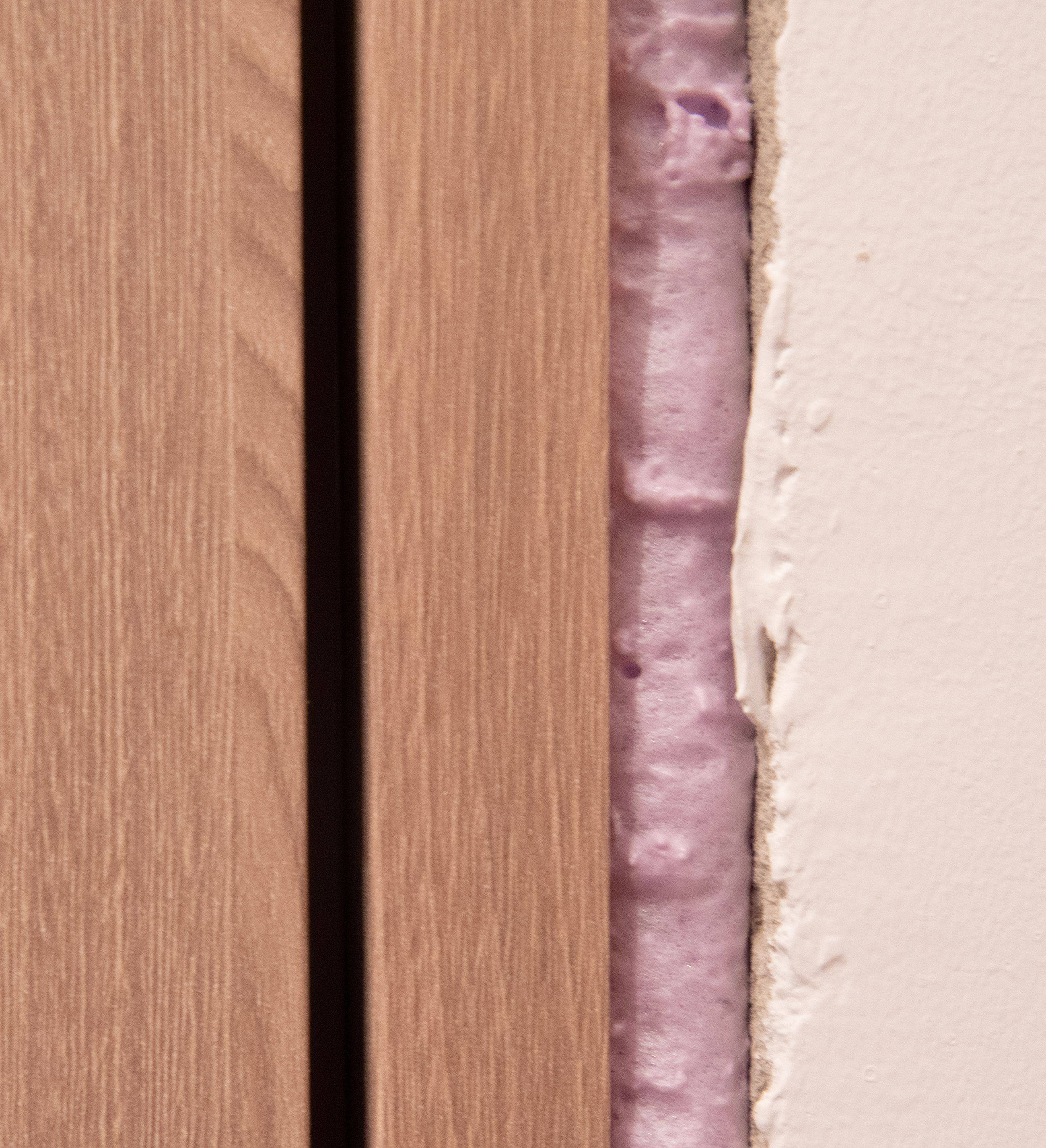 Close-up of wooden panels revealing insulation behind a wall.