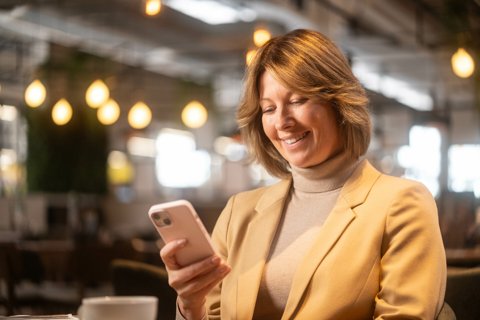 Smiling woman using a smartphone in a cafe