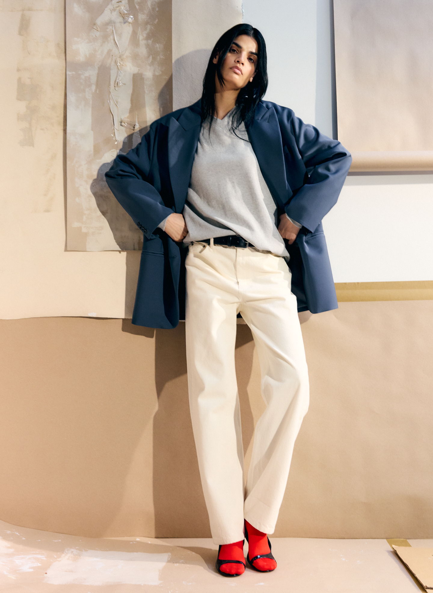 Person in stylish outfit with gray top, navy jacket, and red shoes.