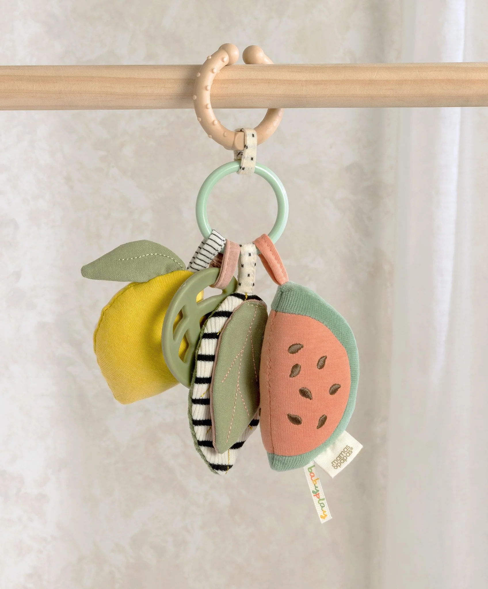 Colorful fruit-shaped toys hanging from a wooden ring.