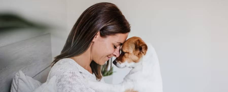 A young woman hugs her dog at home