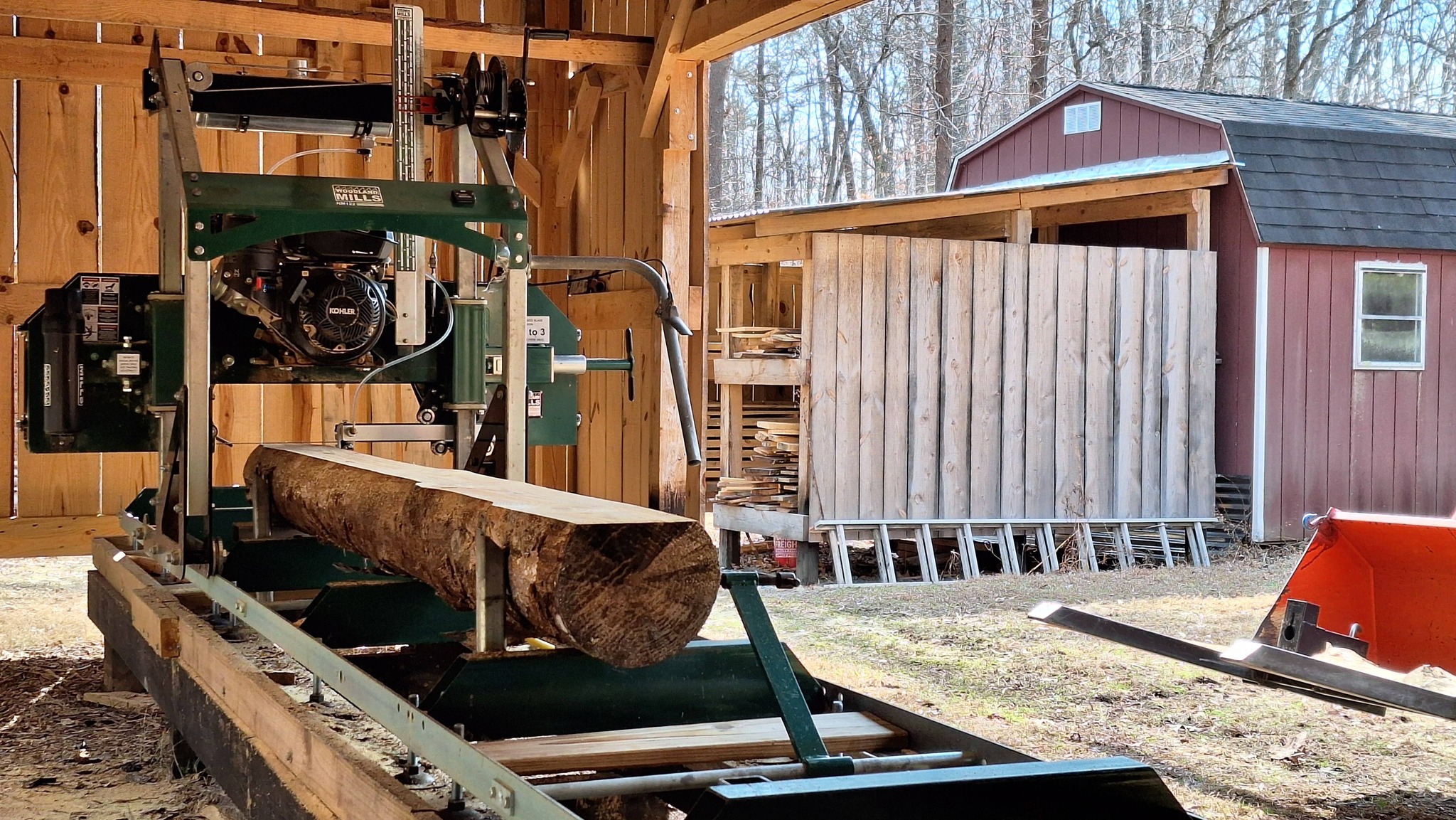 A sawmill with a log inside a wooden structure.