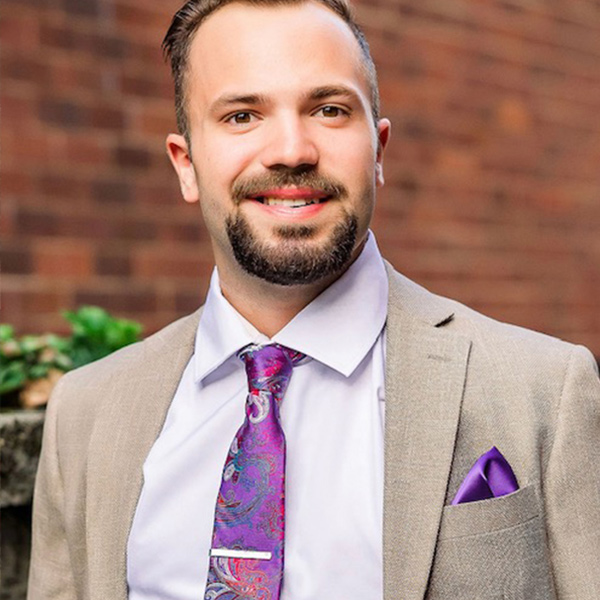 Man wearing a purple paisley tie with a tan suit
