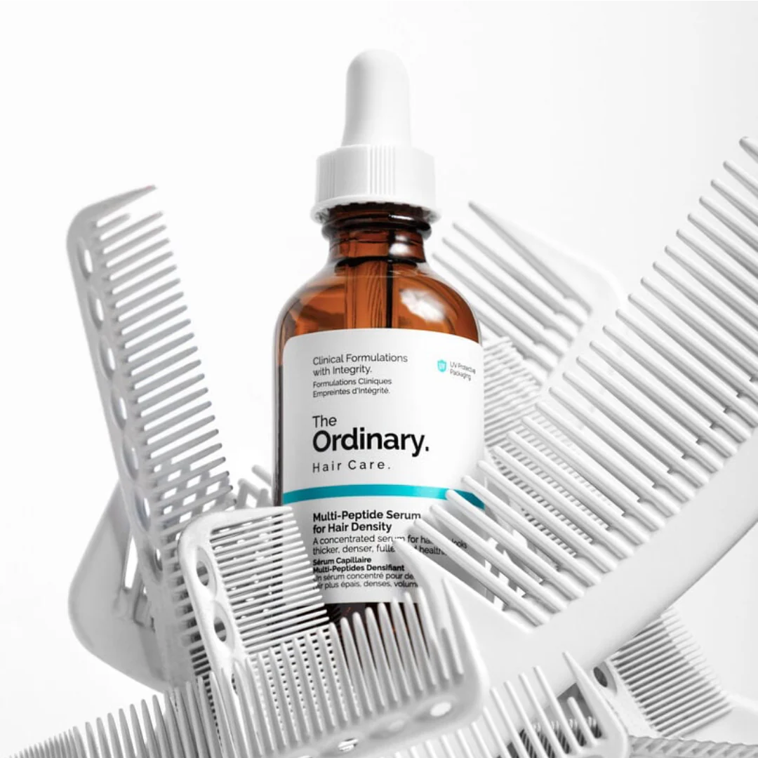 Brown bottle of serum surrounded by white hair combs.