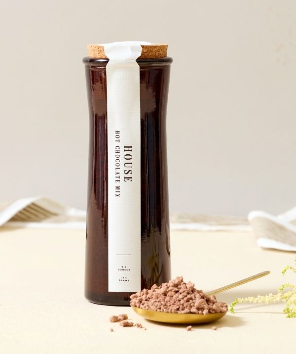 Bottle of cocoa powder with a wooden spoon on a light background.