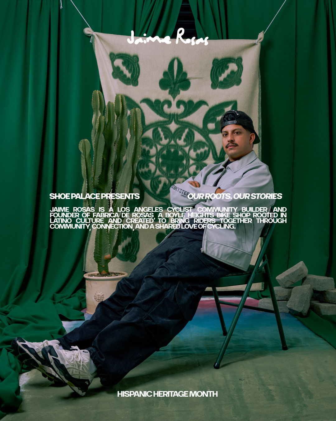 Person sitting in a chair in front of a green backdrop with plants.
