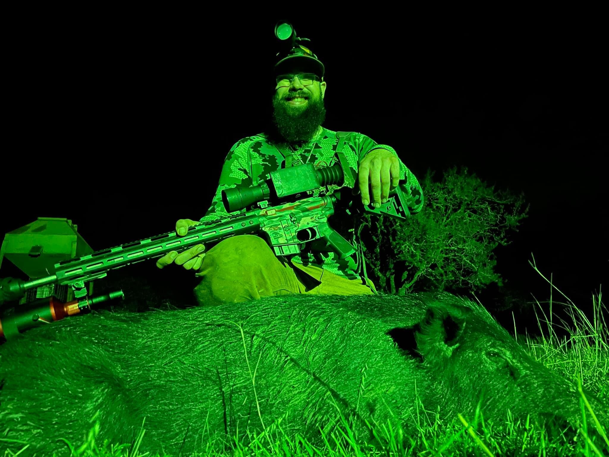 Hog hunter using a green Sniper Hog Light for night hunting