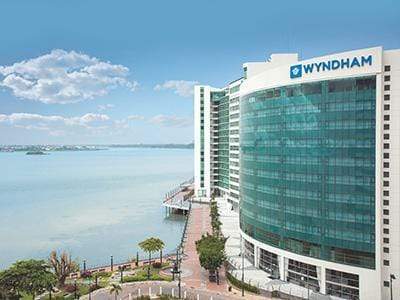 Exterior view of the hotel. It is white with blue windows. You can see the ocean.