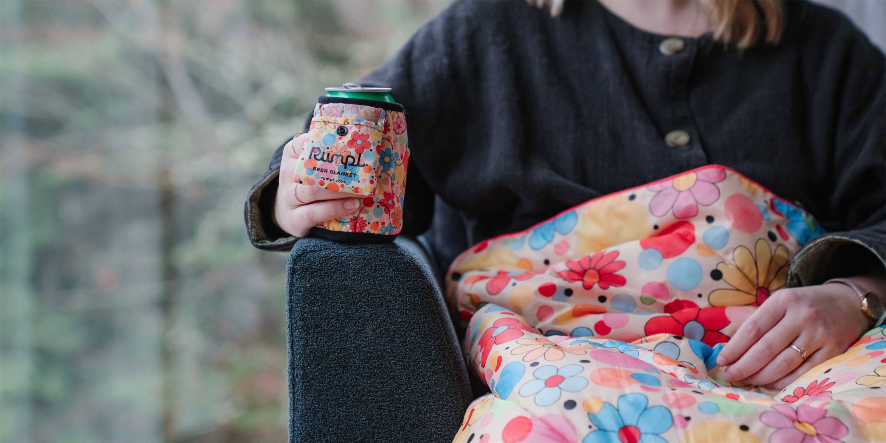 Woman sitting on a couch with a flower beer blanket and flower rumpl blanket