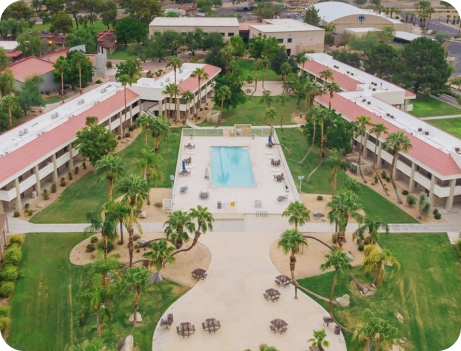 Aerial view of a hotel with a pool and palm trees.