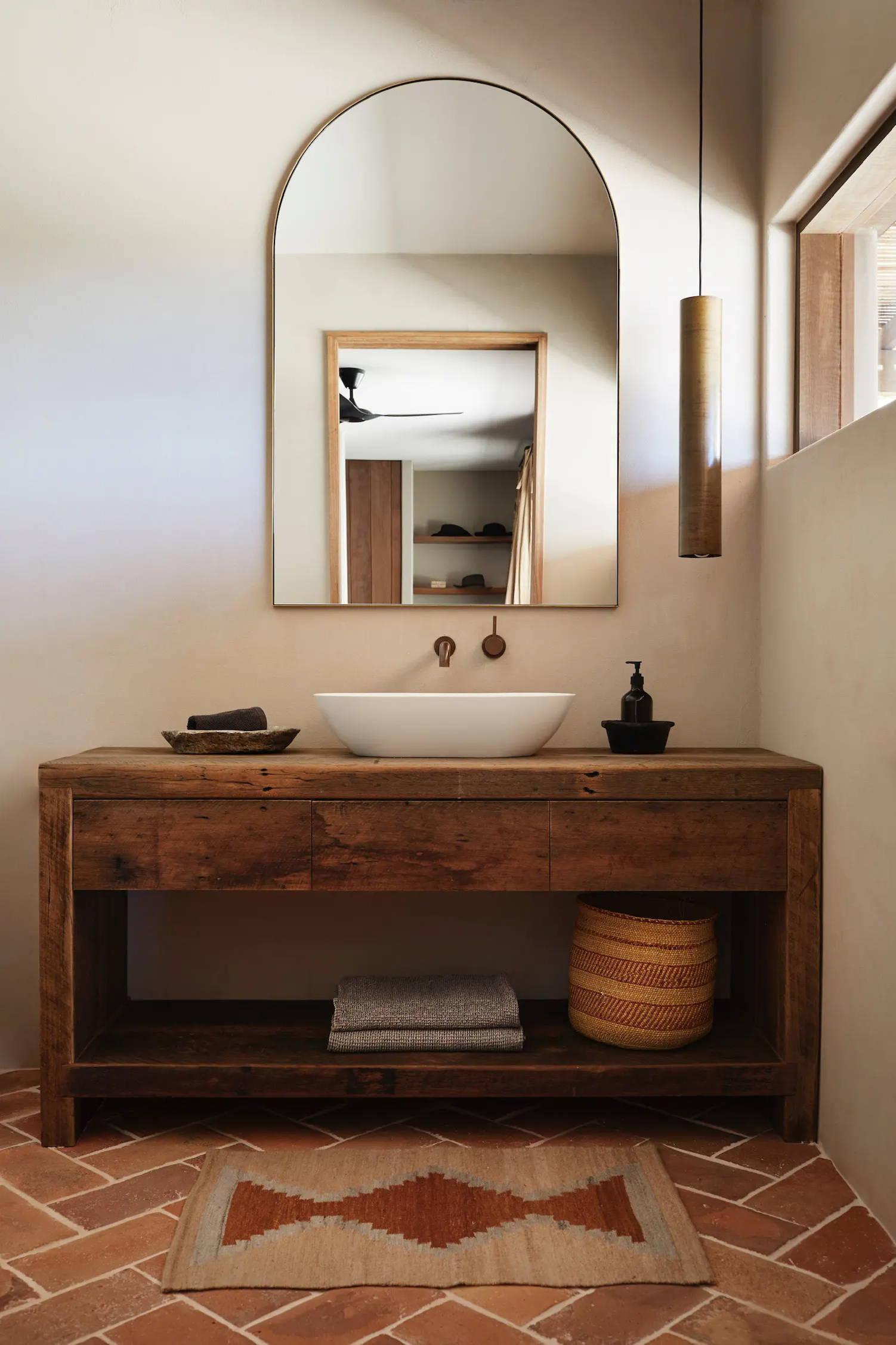 Modern bathroom with wooden vanity, mirror, and pendant light.
