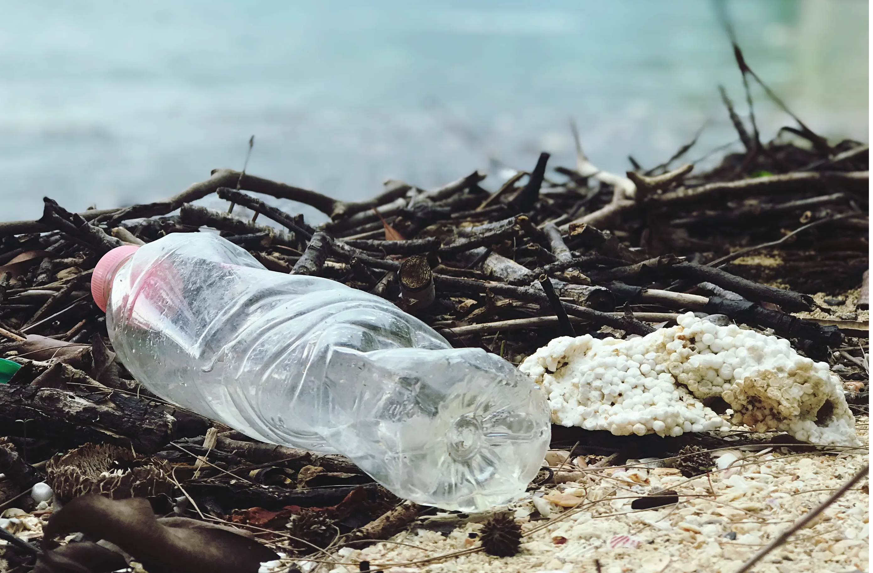 A water bottle and plastic beads on a beach