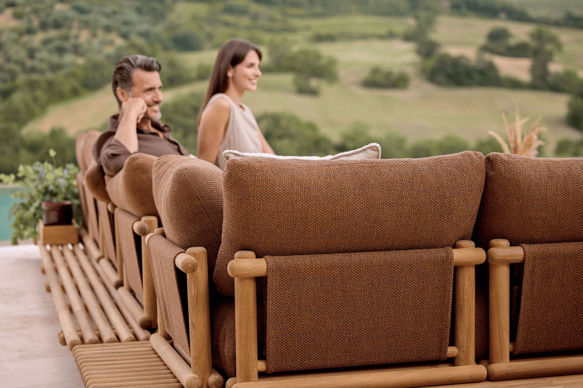 Luxury outdoor sectional with wood frame and performance cushions overlooking a scenic landscape.
