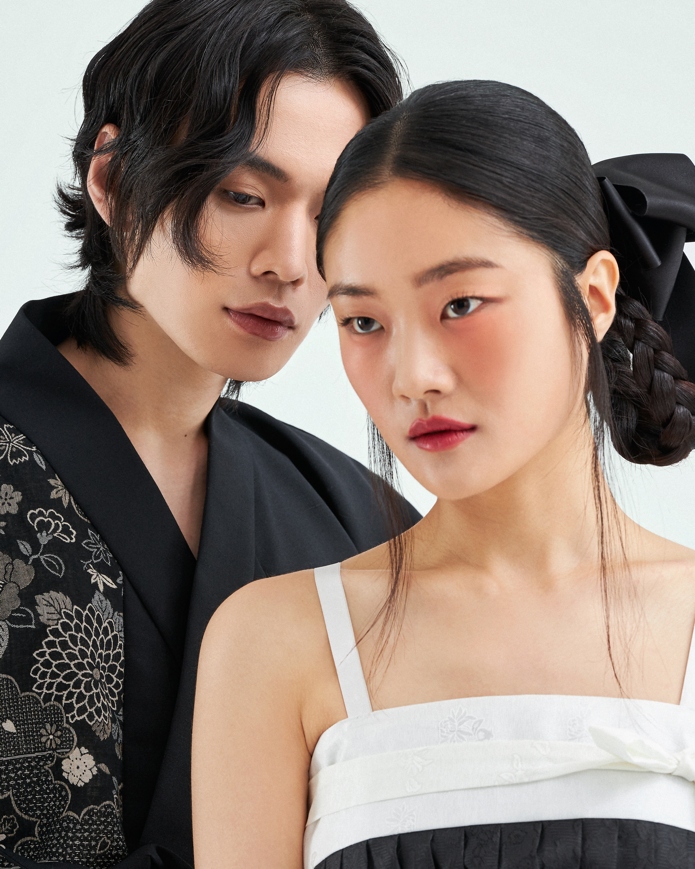 A man and woman in stylish attire, posing closely together.