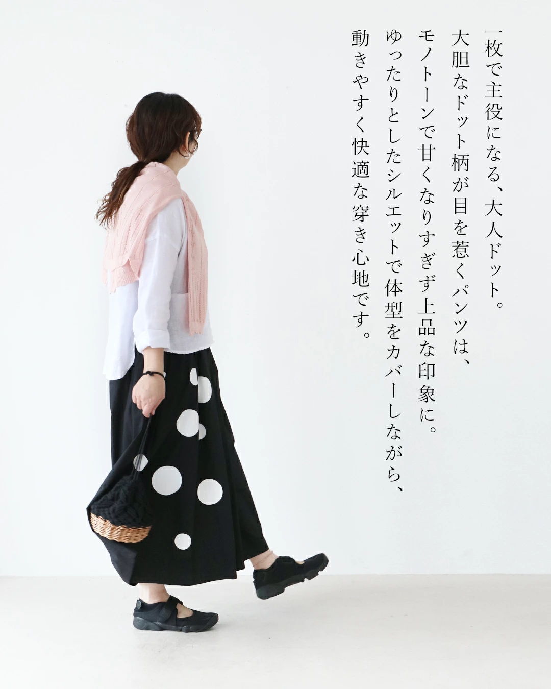 A woman in a white shirt and polka dot skirt, wearing a pink scarf.