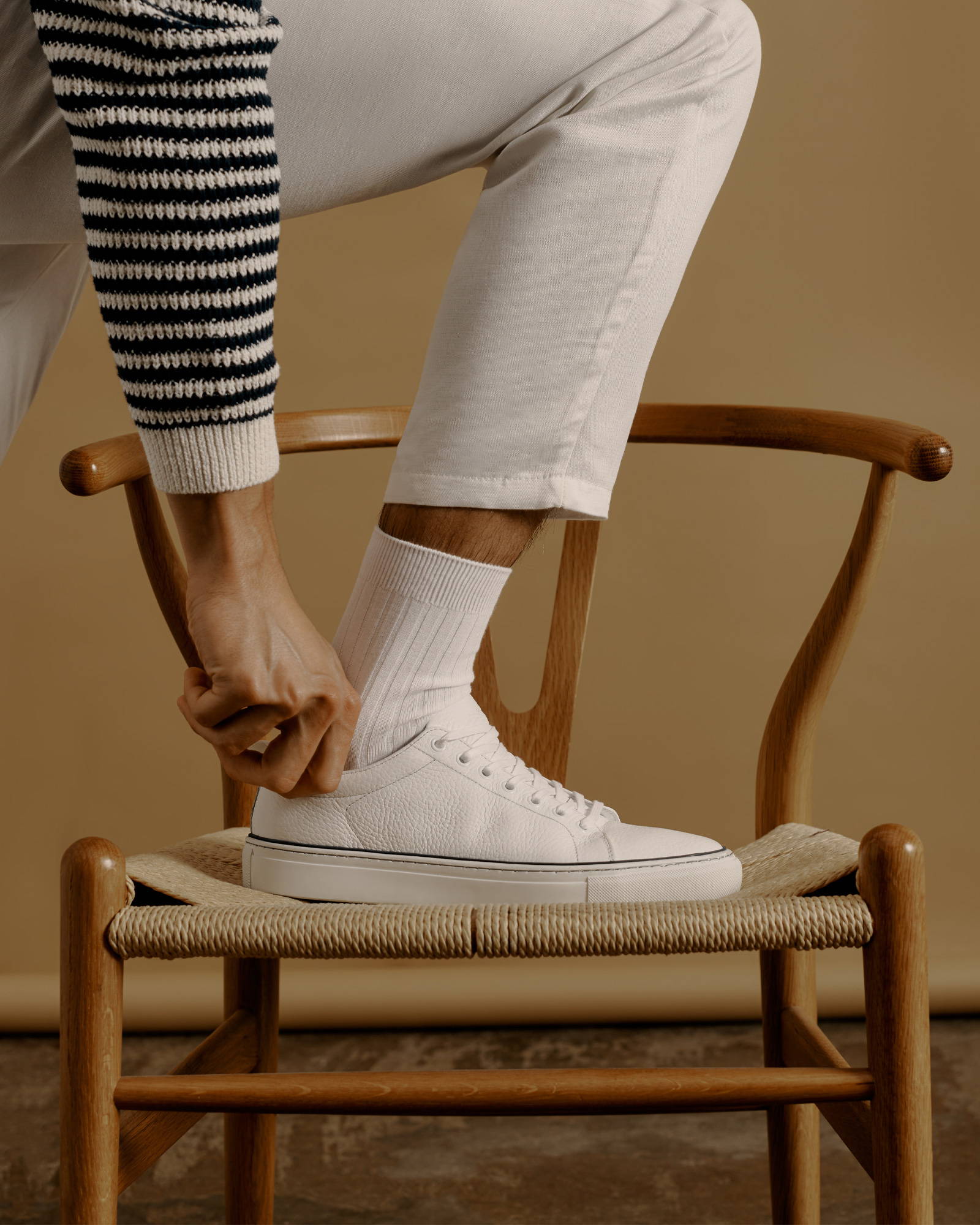 The Royale White Sneakers worn with cream chinos and a stripe knit
