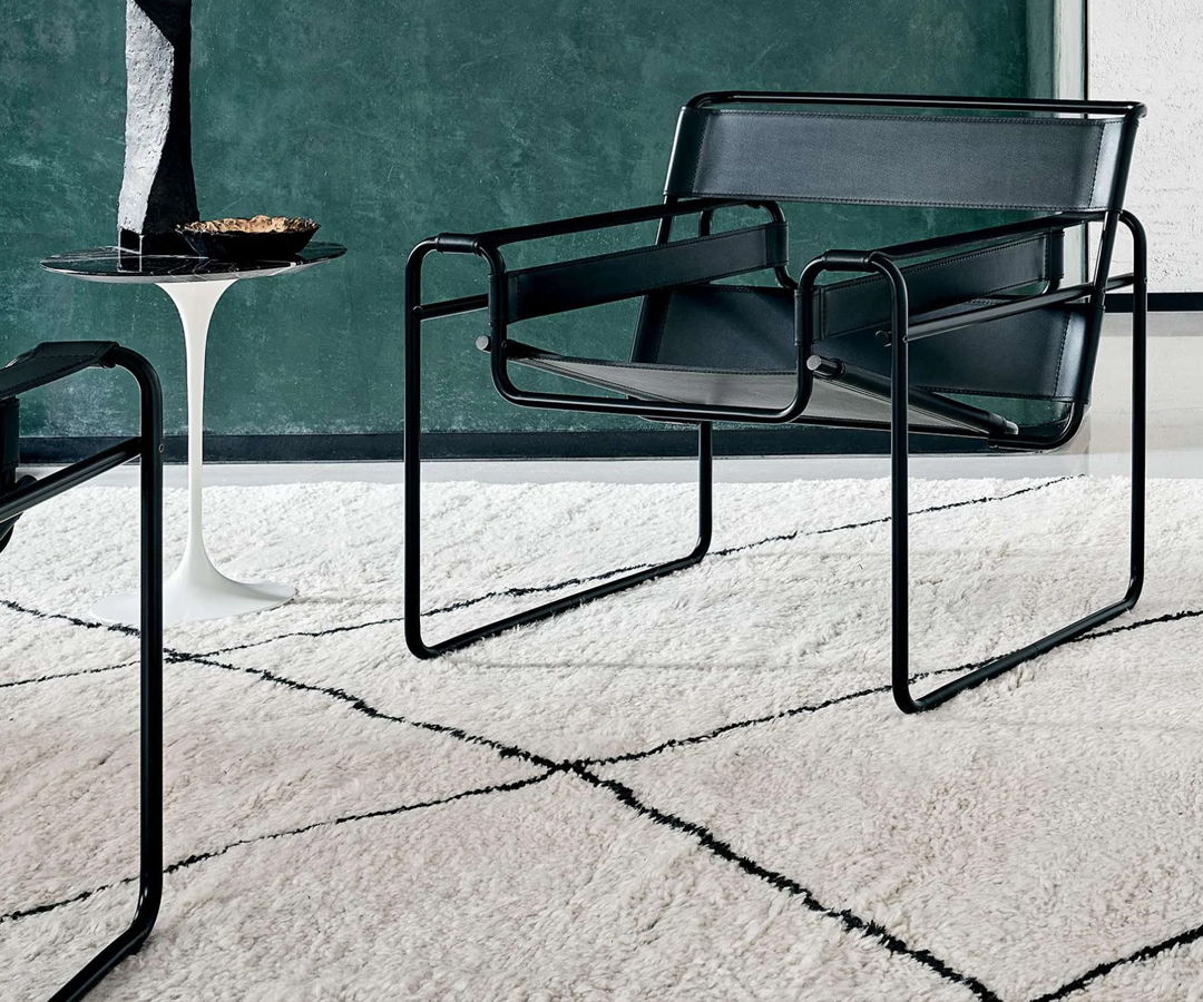 Black Wassily armchair by Knoll and Marcel Breuer on a patterned rug with a side table.