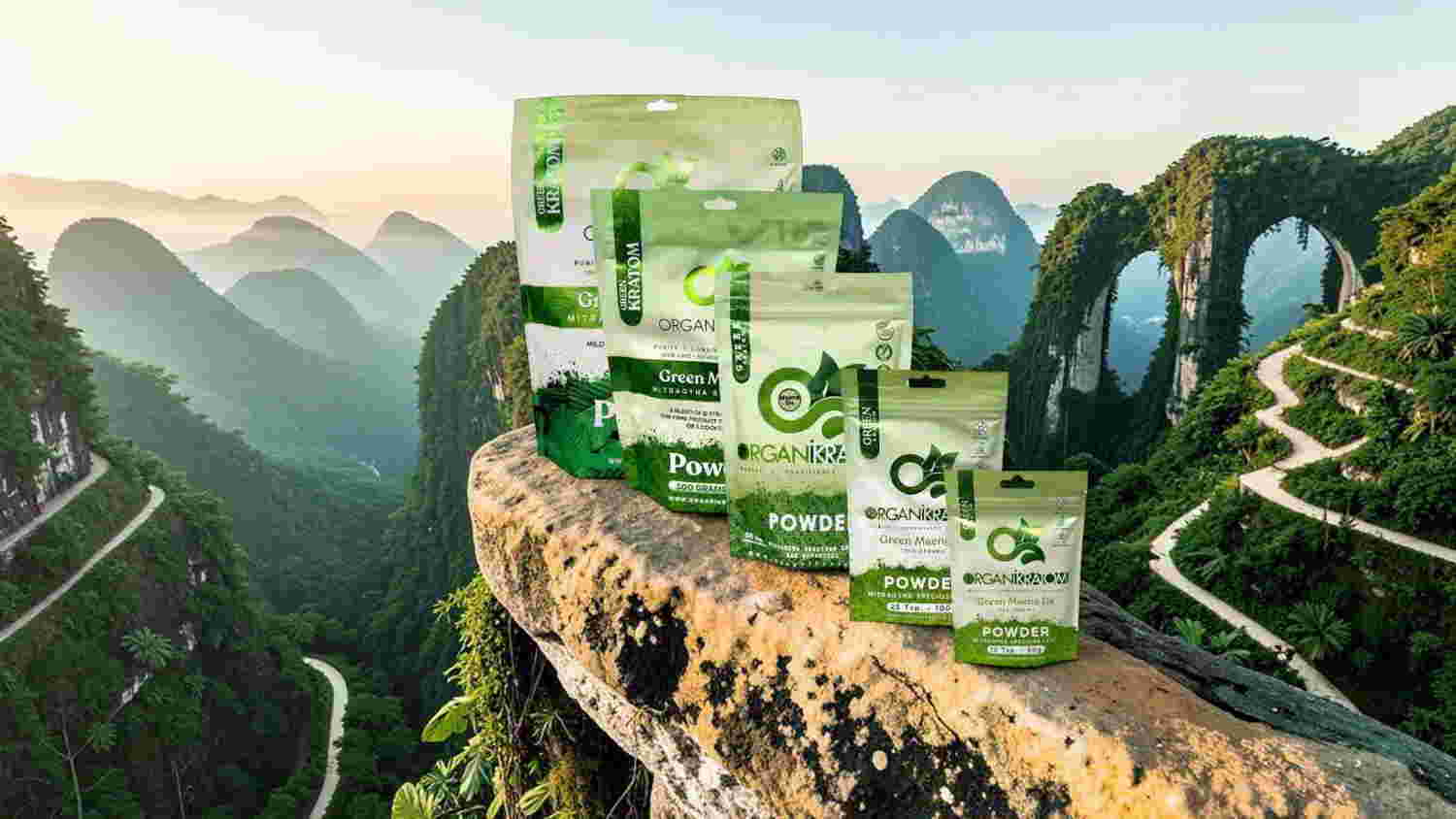 Various green product packages displayed on a rocky ledge with mountains in background.