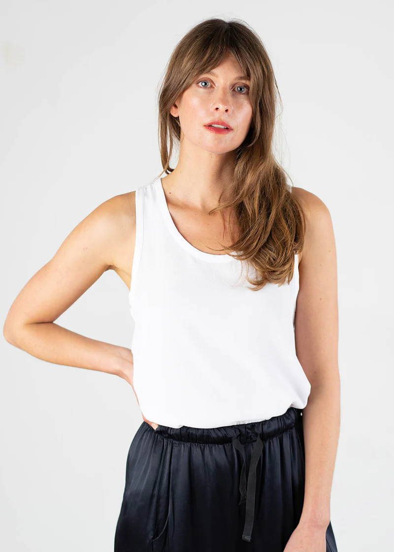 A model wearing a white, sleeveless top with black trousers