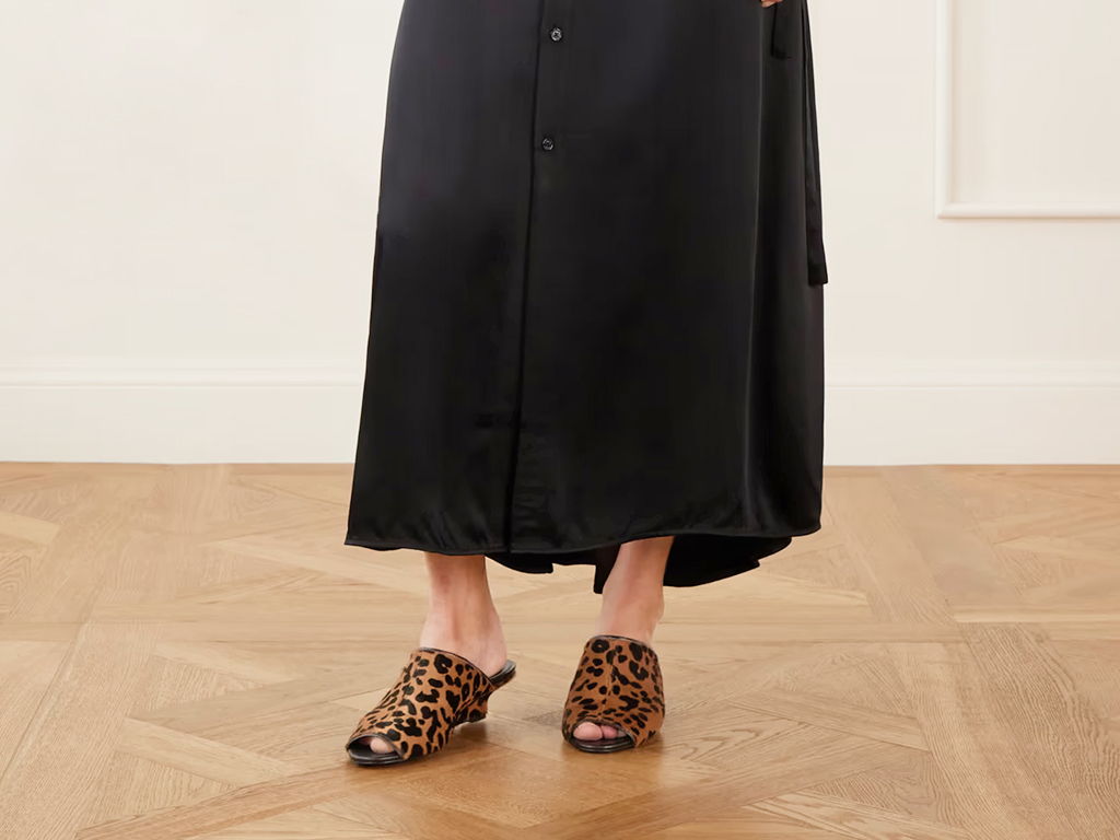 Person wearing a long black dress and leopard print slippers.