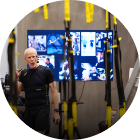 Man demonstrating workout techniques with suspension straps in a gym setting.