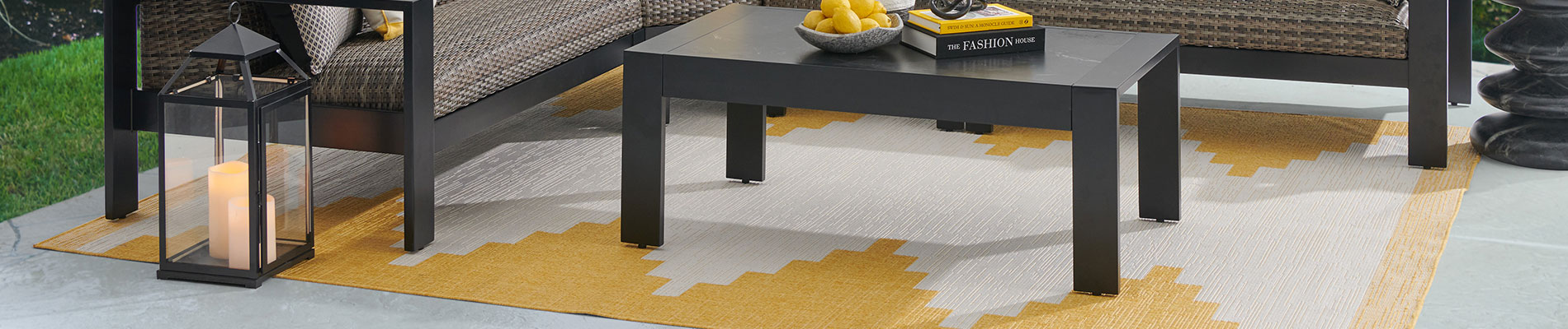Outdoor seating area with a table, rug, and decorative lantern.